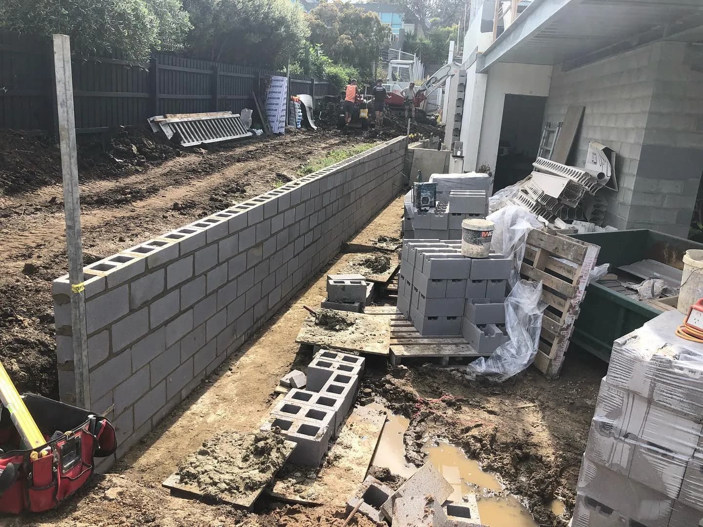 Long charcoal-block retaining wall under construction