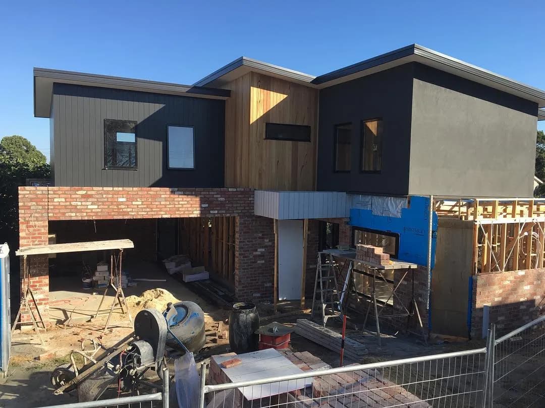 Contemporary home in progress, red-brick lower with dark upper level