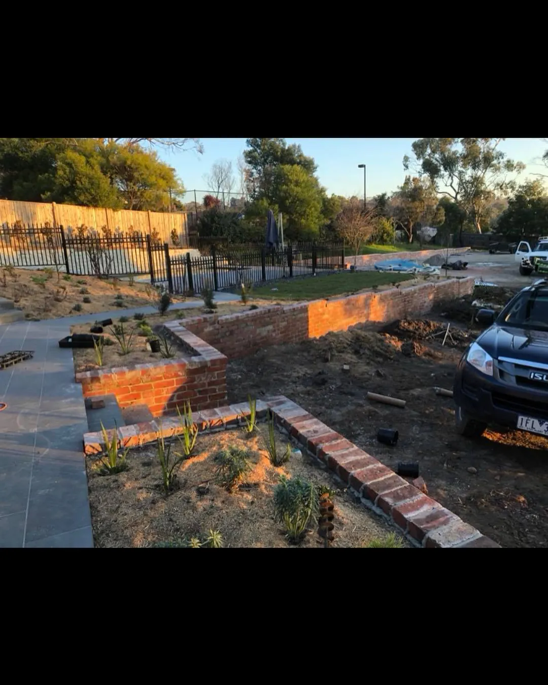 L-shaped red-brick raised garden retaining wall in golden hour