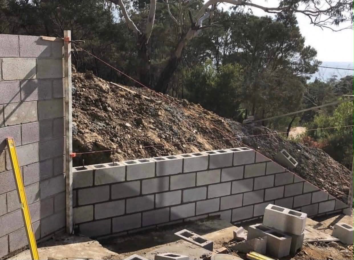 Hillside grey block retaining wall with engineered drainage
